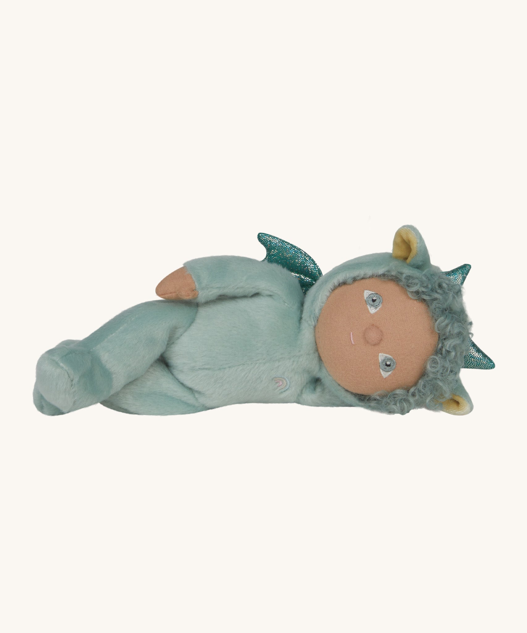 Olli Ella Dante the dragon dinky dinkum doll lying down. A pale green doll with matching curly hair and cute ears. 