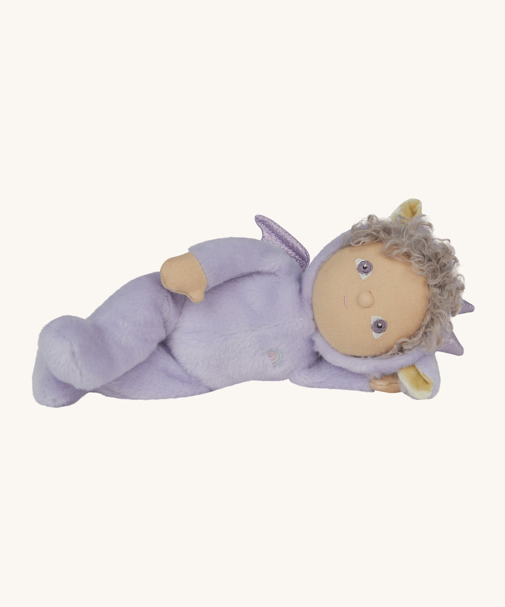 Olli Ella Dante the dragon dinky dinkum doll lying down. A lilac doll with matching curly hair and cute dragon ears. 