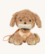 The Olli Ella Dinkum Dog - Goldie is wearing their harness and is holding their plush toy bone in their mouth