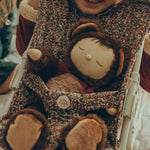 A child sat behind an Olli Ella Stroller in Garland print, has put Olli Ella Cozy Dinkums - Teddy Twiggy inside the stroller.