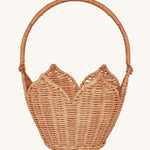 Olli Ella Rattan Poinsettia Carry Basket is a beautiful scalloped, handwoven, rattan basket in a light brown, with a carry handle. The basket is on a cream background.