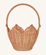 Olli Ella Rattan Poinsettia Carry Basket is a beautiful scalloped, handwoven, rattan basket in a light brown, with a carry handle. The basket is on a cream background.
