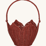 Olli Ella Rattan Poinsettia Carry Basket is a beautiful scalloped, handwoven, rattan basket in a poinsettia red colour, with a carry handle. The basket is on a cream background.