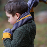A child putting on the Dreamy Blue knitted scarf on their neck. The child is also wearing the Dreamy blue stripe mittens