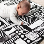 A child laying down, looking intensly at the monochromatic shape print, and enjoying the different shapes