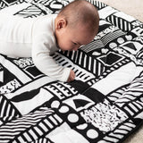 A child laying down, looking intensly at the monochromatic shape print, and enjoying the different shapes
