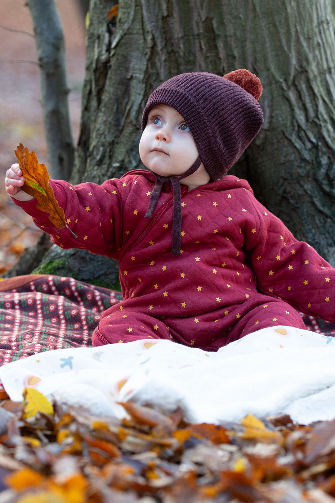 Small child wearing Little Green Radicals Organic kids clothing and winter hat, in a forest to represent the clothing at Babipur. 