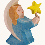 A Ostheimer wooden angel figure holding a star, available at Babipur. This handmade and hand painted festive figure has a blue dress and brown hair holding a yellow star