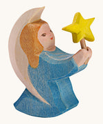 A Ostheimer wooden angel figure holding a star, available at Babipur. This handmade and hand painted festive figure has a blue dress and brown hair holding a yellow star