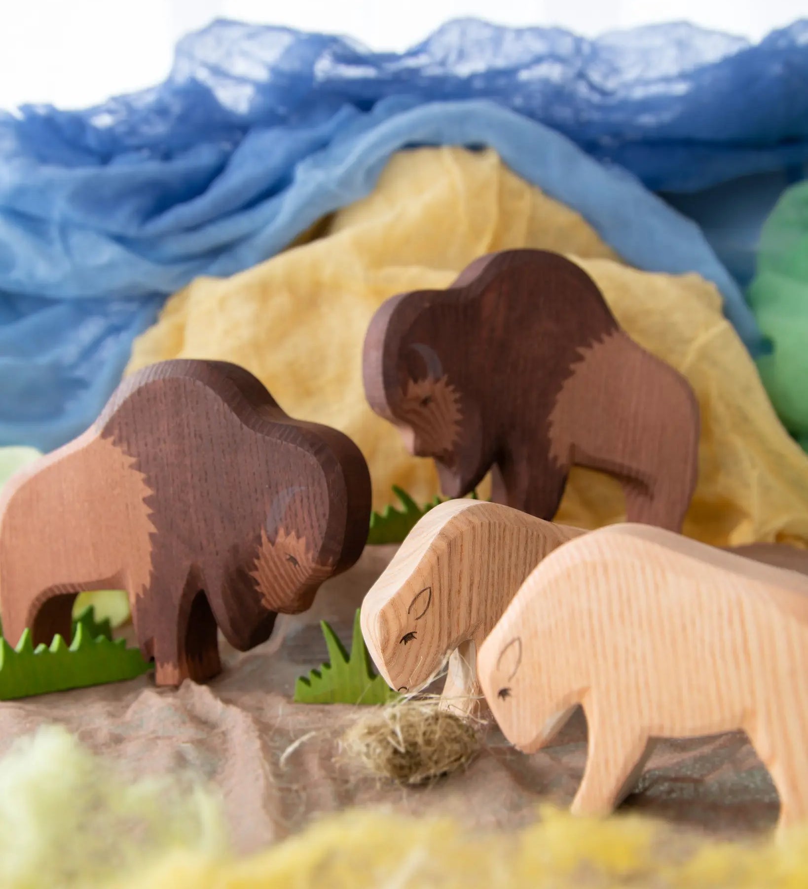 Ostheimer wooden toy Bison family in small world play scene using Ostheimer scarves and grass.