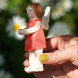 An adult hand holding the Ostheimer wooden 'Sumselinchen' character figure from the German story “Pepe and Sumselinchen”available at Babipur.