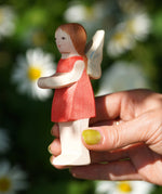 An adult hand holding the Ostheimer wooden 'Sumselinchen' character figure from the German story “Pepe and Sumselinchen”available at Babipur.