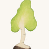 Ostheimer Small Wooden Birch Tree, handmade and hand crafted with a light green painted top to represent leaves, and painted bark and trunk detail. The smooth natural wood grain shows through making the tree more realistic. The tree is on a cream backgroud