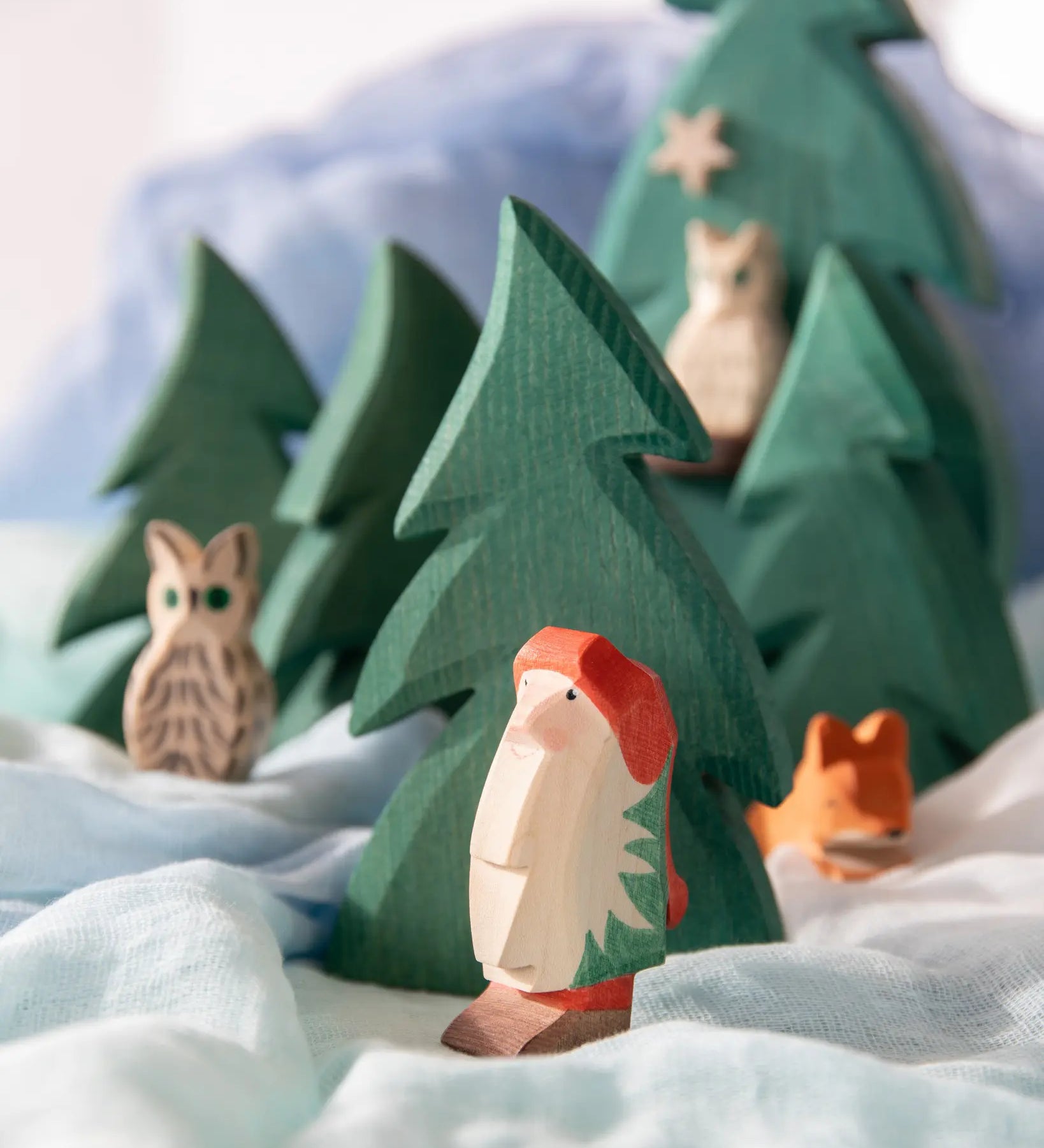 Ostheimer Norbert toy, a wooden gnome from Daniela Drescher book. Long white beard, red winter hat and brown boots in a play scene.