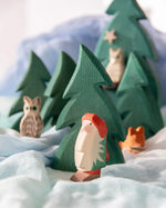 Ostheimer Norbert toy, a wooden gnome from Daniela Drescher book. Long white beard, red winter hat and brown boots in a play scene.