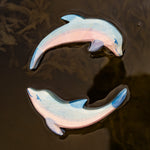 A close up of the Ostheimer wooden dolphin figure with its head held high and the diving dolphin floating on water and showing the hand painted detail.