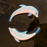 A close up of the Ostheimer wooden dolphin figure with its head held high and the diving dolphin floating on water and showing the hand painted detail.