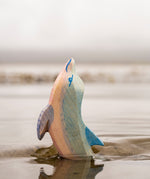 A close up of the Ostheimer wooden dolphin figure with its head held high coming out out water showing the hand painted detail.