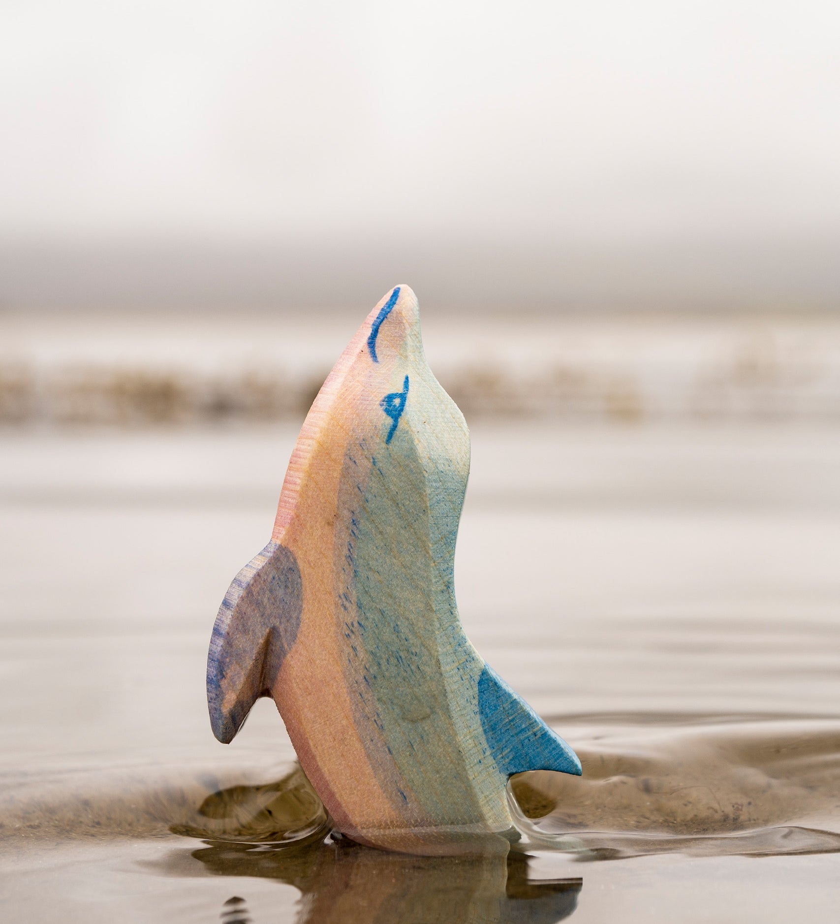 A close up of the Ostheimer wooden dolphin figure with its head held high coming out out water showing the hand painted detail.
