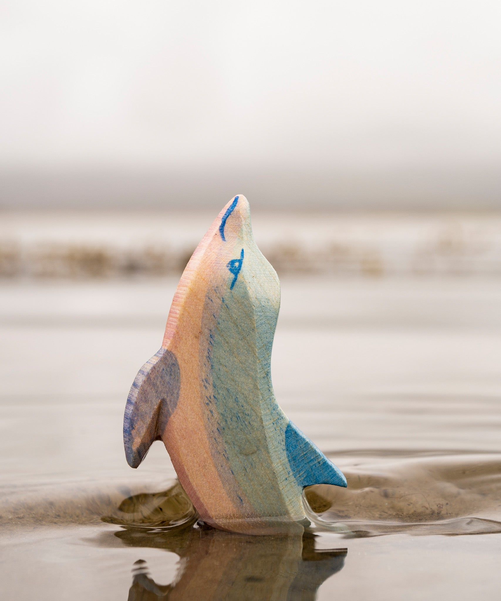 A close up of the Ostheimer wooden dolphin figure with its head held high coming out out water showing the hand painted detail.