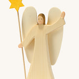 A wooden Ostheimer angel wearing a white gown holding a Ostheimer wooden star on a cream background