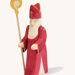 A Ostheimer wooden St Nicholas figure with moving arms holding a wooden staff on a cream background
