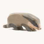 A wooden Ostheimer badger figure with its head low on a cream background.