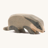 A wooden Ostheimer badger figure with its head low on a cream background.