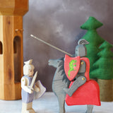The Ostheimer handmade from Germany Wooden Blue Standing Knight Figure standing next to the Black Knight and Horse set deal for a fantasy world storytelling and open-ended play, sold at Babipur