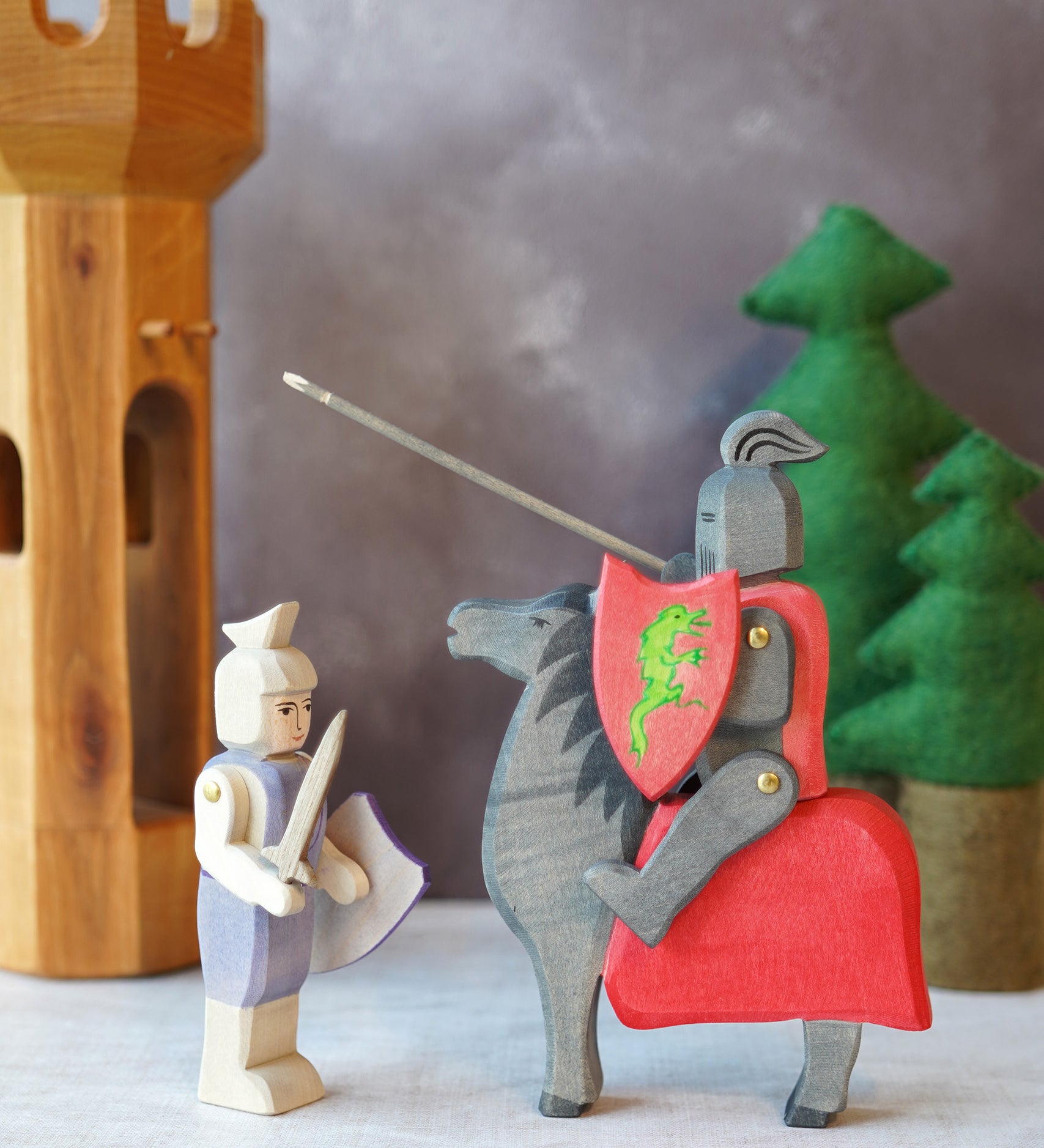 The Ostheimer handmade from Germany Wooden Blue Standing Knight Figure standing next to the Black Knight and Horse set deal for a fantasy world storytelling and open-ended play, sold at Babipur