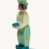 A oriental wooden Ostheimer king figure wearing a green gown on a cream background.