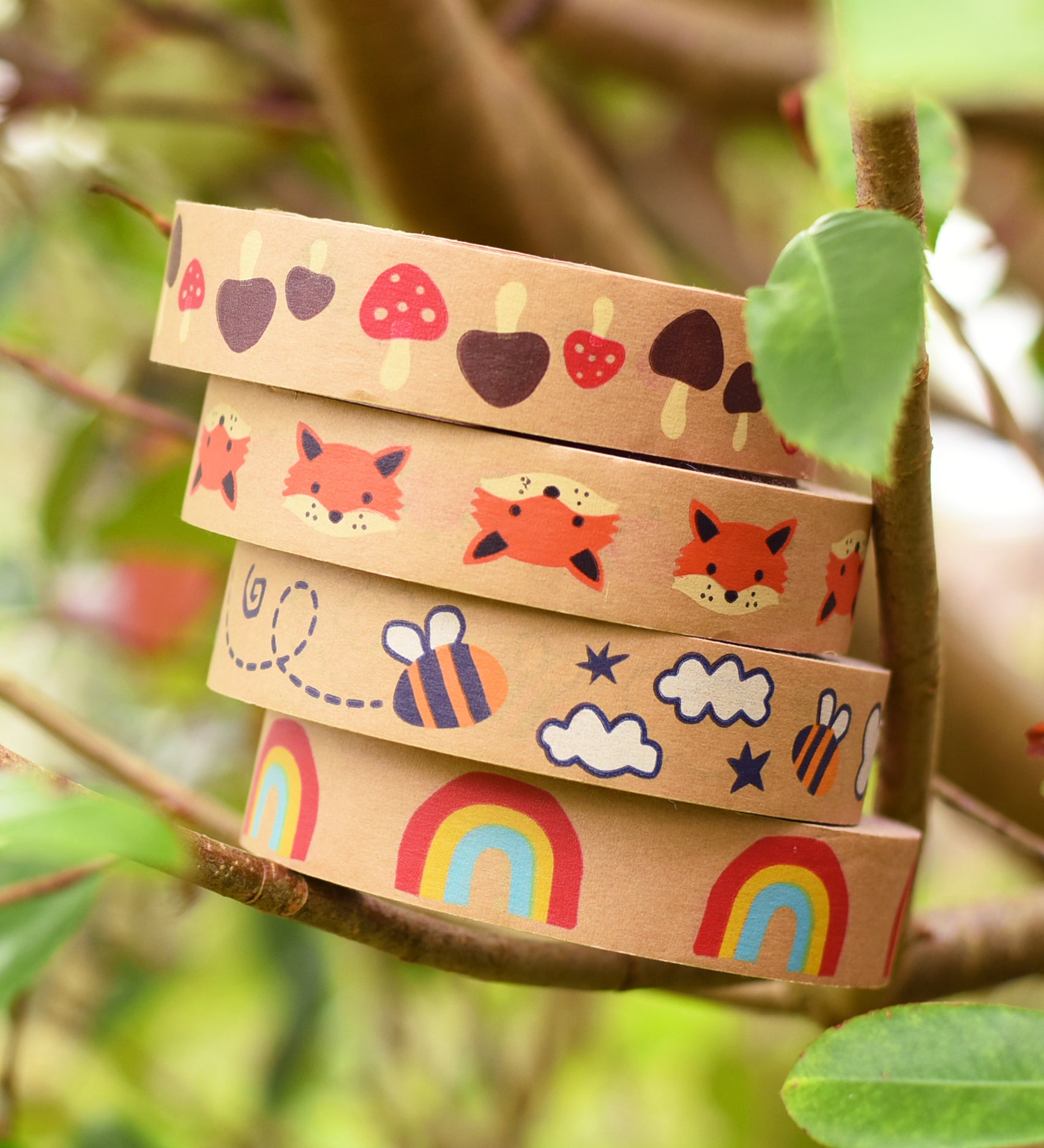 A stack of Babipur Kraft Eco Paper Tape including Mushroom, Fox, Bee and Rainbow, in an outdoor setting