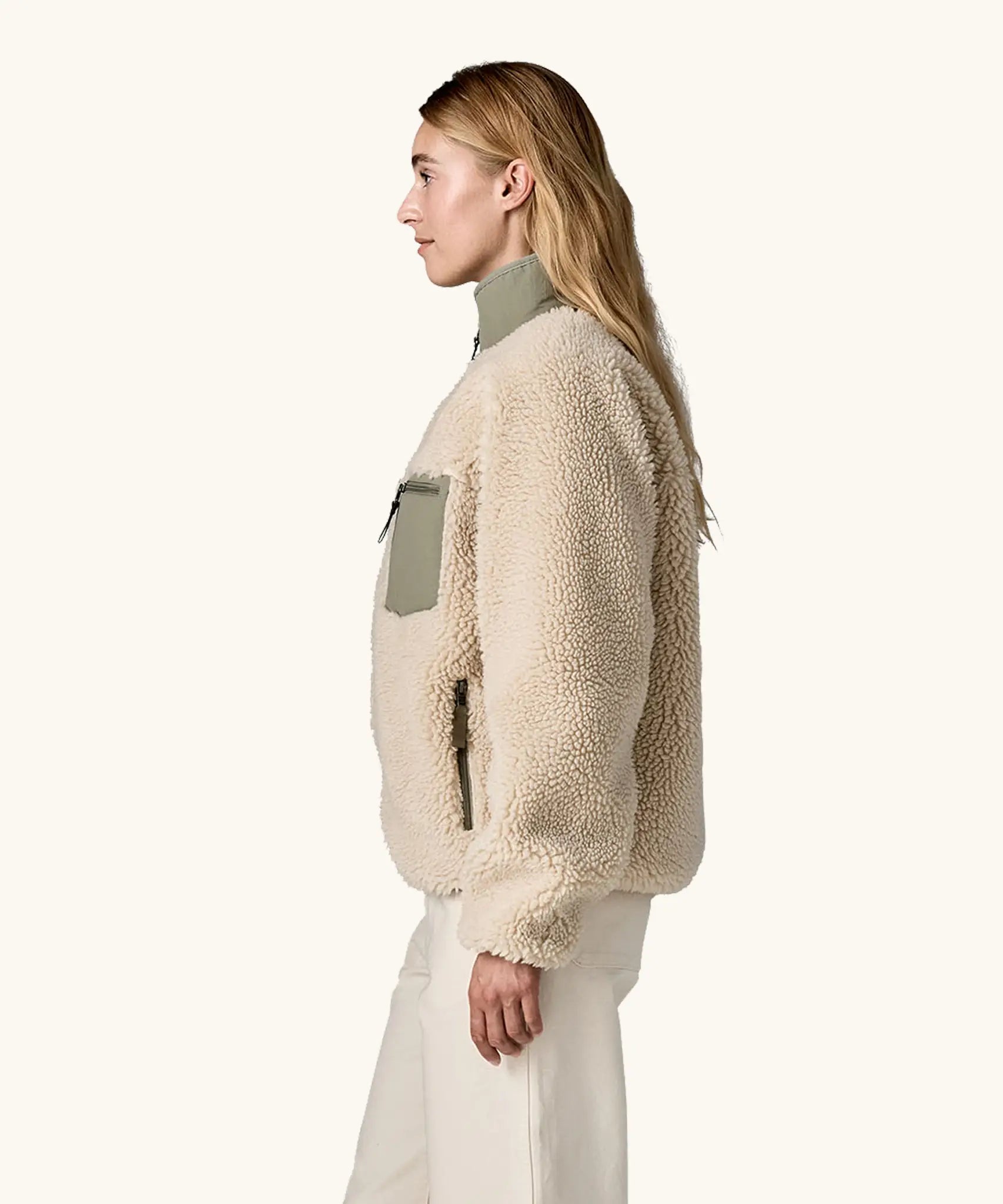 side view of woman wearing Patagonia Women's Classic Retro-X® Fleece Jacket in Dark Natural w/River Rock Green, green zip pocket visible. 