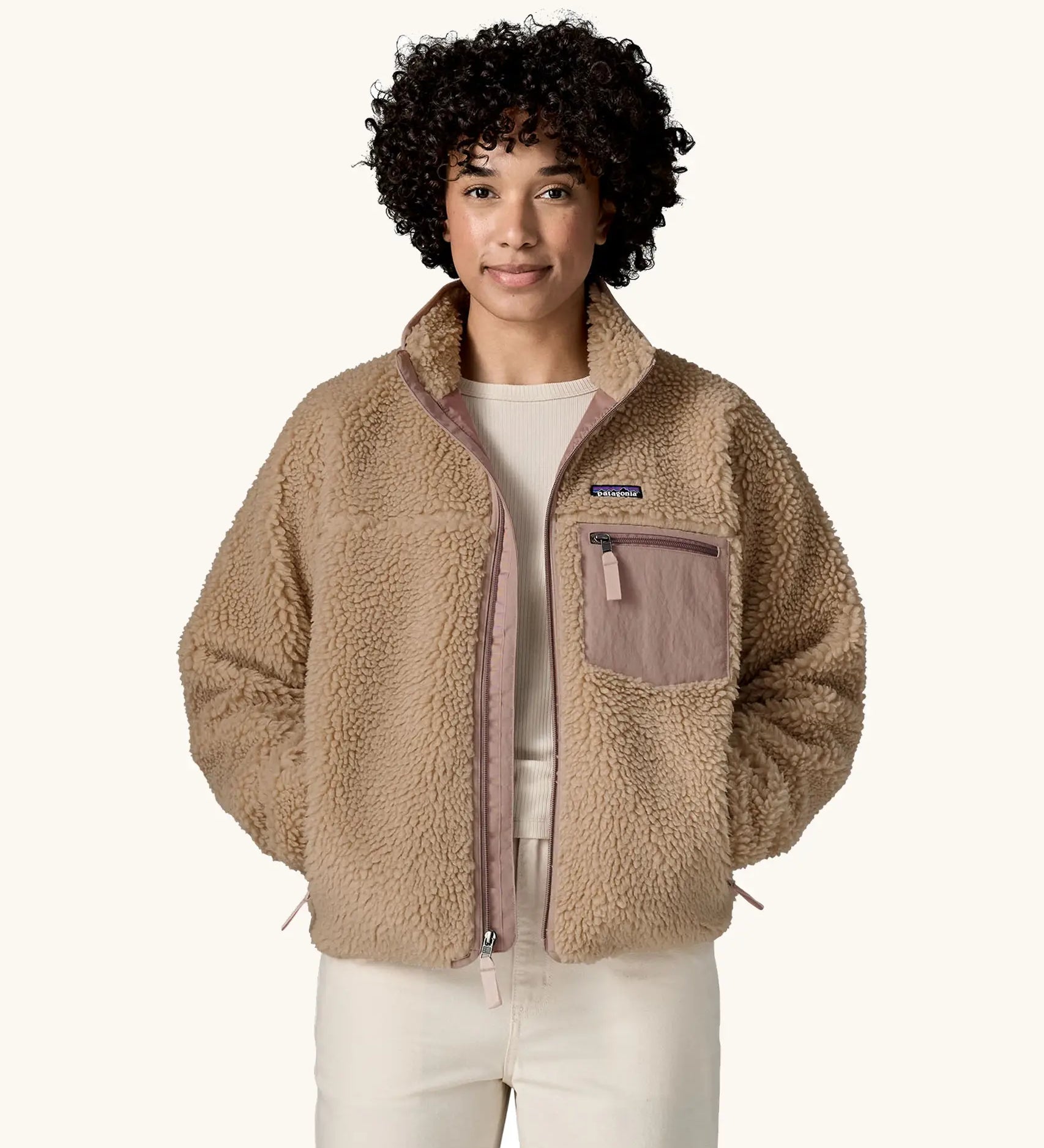 Woman wearing Patagonia Women's Classic Retro-X® Fleece Jacket in oar tan, undone zip, hands in both side pockets. 