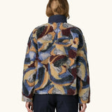Back of Woman wearing Patagonia Women's Classic Retro-X® Fleece Jacket in Smudge, Smolder Blue. The Blue, cream, green and brown smudge pattern visible.