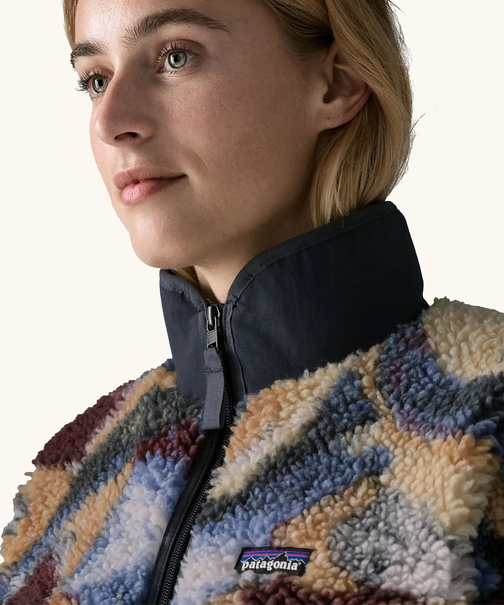 Close up of collar, zip and patch stitched Patagonia logo on Patagonia Women's Classic Retro-X® Fleece Jacket in Smudge, Smolder Blue, worn by a woman.