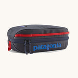 Patagonia 3L black hole cube travel bag in smolder blue/ amanita red available at Babpipur. A dark blue travel bag with a zip fastener with the brand name on the top panel