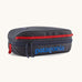 Patagonia 3L black hole cube travel bag in smolder blue/ amanita red available at Babpipur. A dark blue travel bag with a zip fastener with the brand name on the top panel