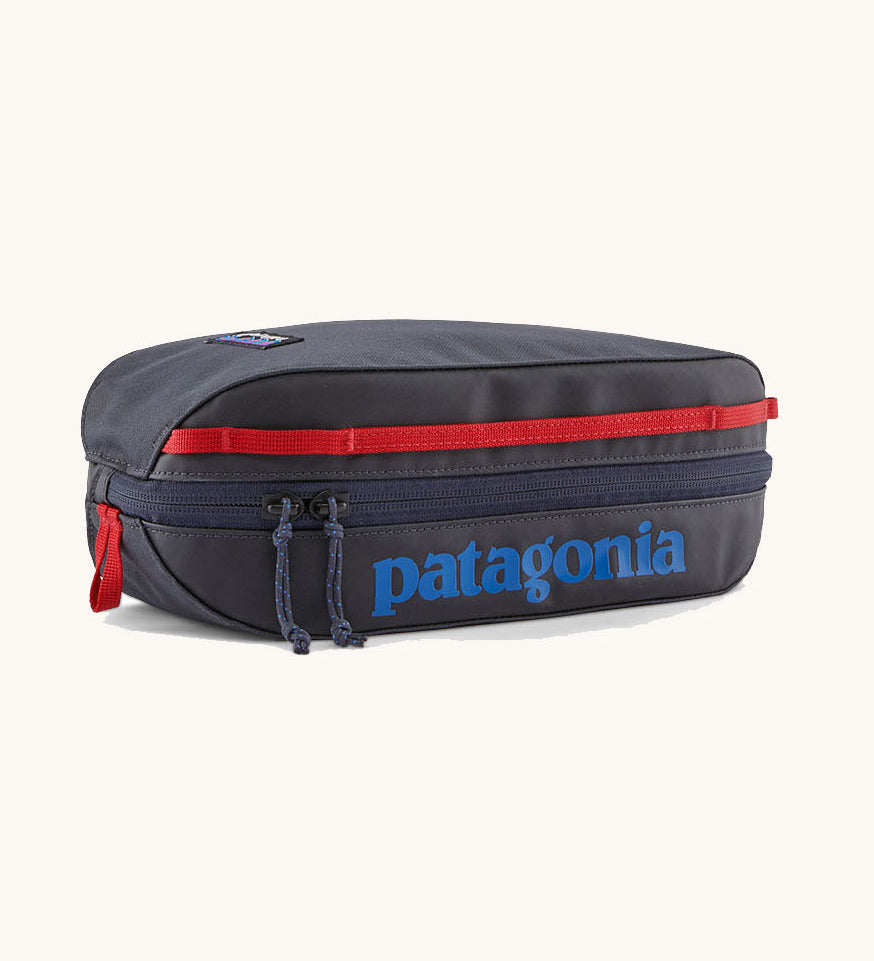Patagonia 3L black hole cube travel bag in smolder blue/ amanita red available at Babpipur. A dark blue travel bag with a zip fastener with the brand name on the top panel