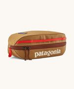 Patagonia 3L black hole cube travel bag in talon hold available at Babpipur. A dark orange travel bag with a brown zip fastener and the brand name on the top panel