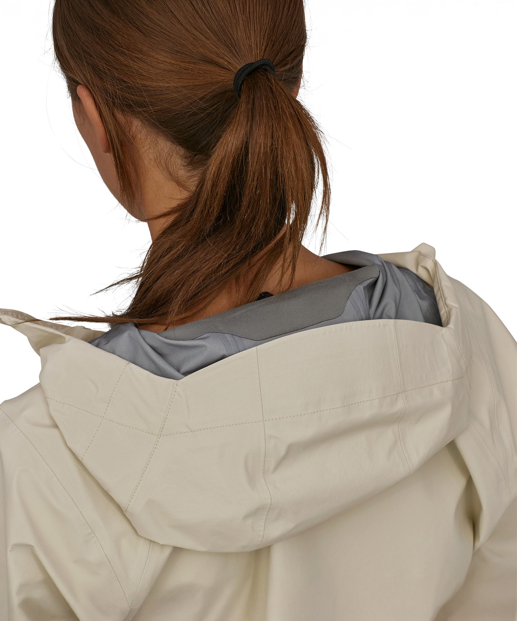 A closer view of the hood on the Patagonia Women's Torrentshell 3L Rain Jacket. The image also shows a person from the back with their hair tied up