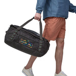 A person carrying the Patagonia Black Hole Duffel 55L in their hands using the carry straps