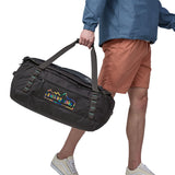 A person carrying the Patagonia Black Hole Duffel 55L in their hands using the carry straps