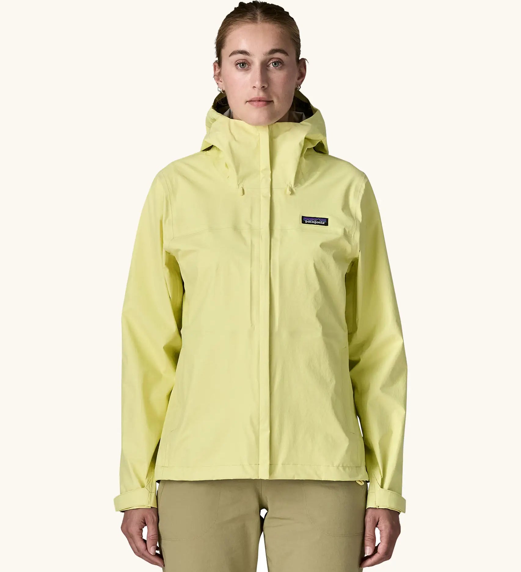 Woman wearing Patagonia Women's Torrentshell 3L Rain Jacket in Vellum Green. with full zip, adjustable hood, zippered handwarmer pockets, and Patagonia logo patch sewn on chest. 