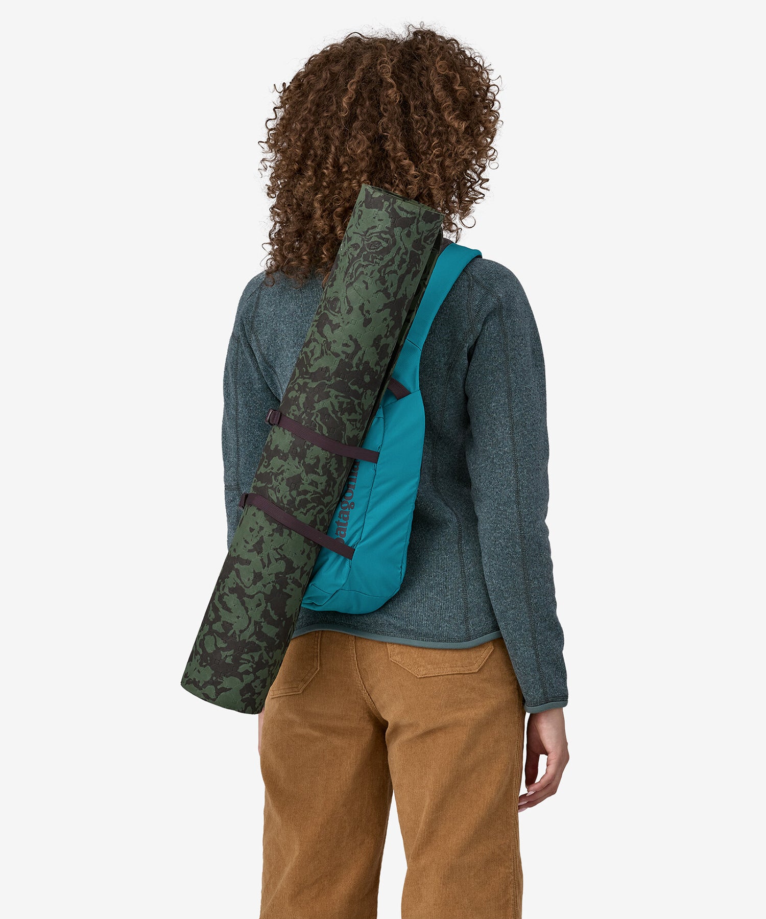 A person carrying a yoga mat in a Patagonia Atom Sling 8L