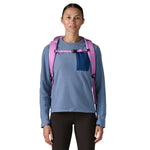 A woman wearing the Patagonia black hole 25 litre backpack in brisk purple available at Babipur 