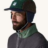 Man wearing Patagonia Adult Range Earflap Cap in denim, and cascade fleece with flap down and tied, available to buy at Babipur.