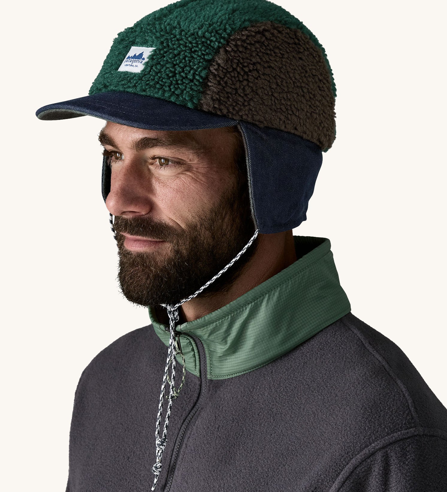 Man wearing Patagonia Adult Range Earflap Cap in denim, and cascade fleece with flap down and tied, available to buy at Babipur.