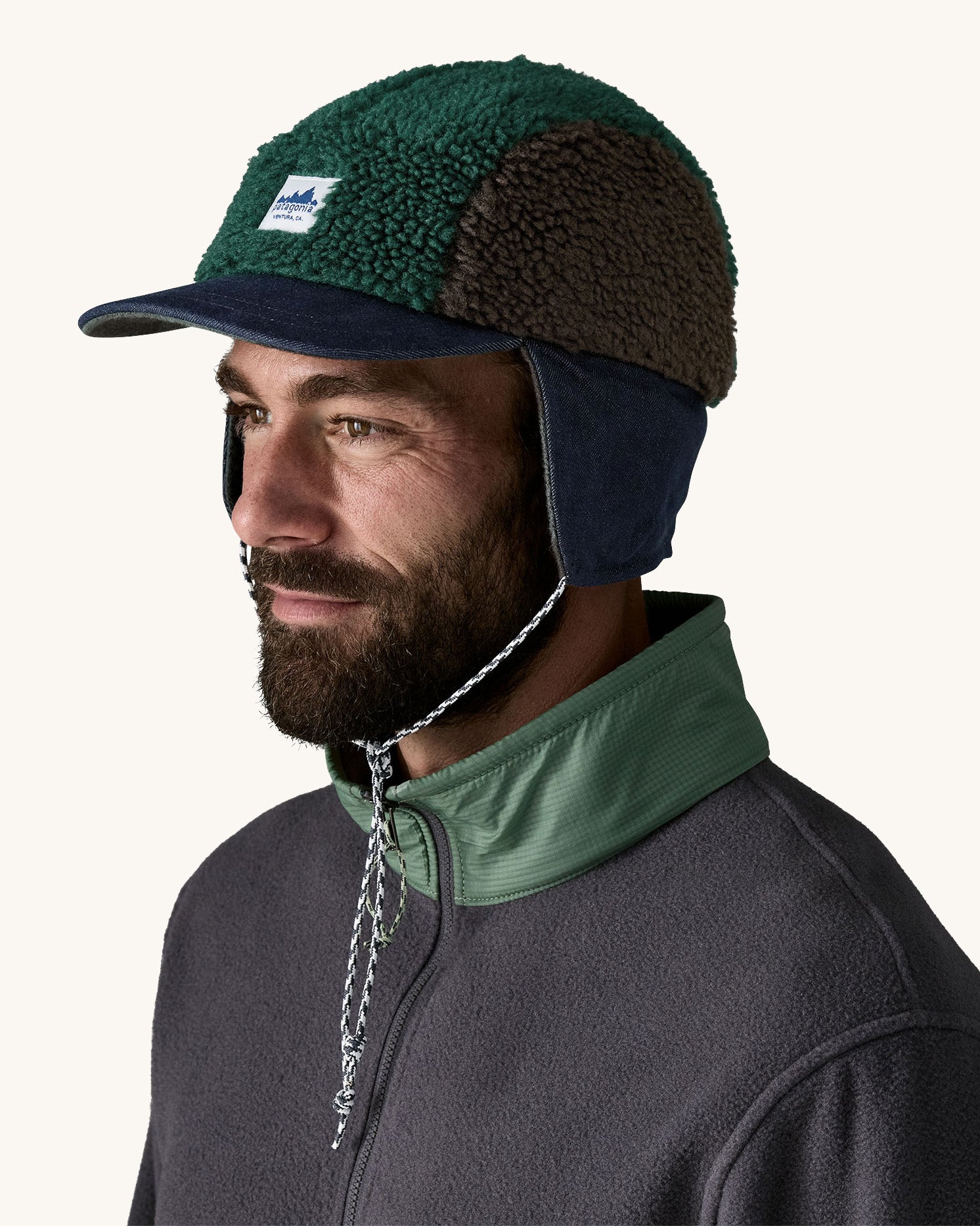 Man wearing Patagonia Adult Range Earflap Cap in denim, and cascade fleece with flap down and tied, available to buy at Babipur.