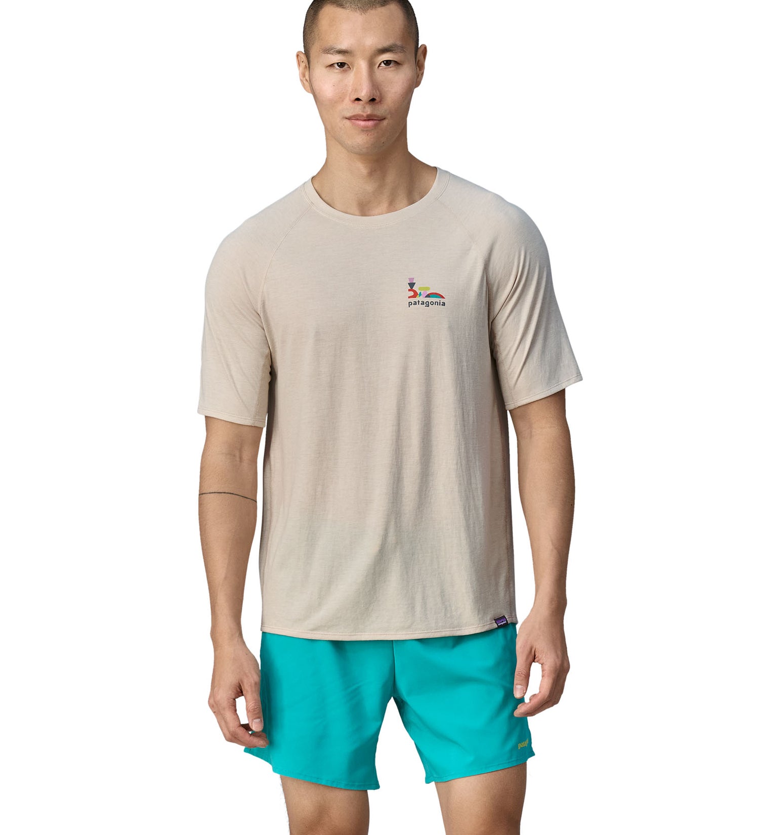 A person wearing light blue shorts, is wearing the Patagonia Men's Cap Cool Trail Graphic T-Shirt to show the fit from the front